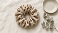 Beige scrunchie on cream linen with eucalyptus